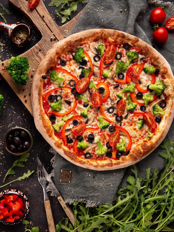 vegetarian-pizza-with-broccoli-red-pepper-tomato-black-olives-wooden-cupboard